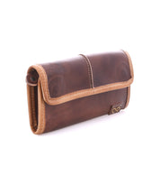 The Bed|Stü Canton is a brown leather wallet with tan trim and a flap closure, designed as a 2-in-1 clutch and wallet, shown positioned at an angle on a white background.