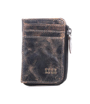 The Bed|Stü Carrie is a compact brown leather wallet featuring visible creases, front card slots, and a zip compartment on the right side, displayed against a white background.