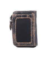 Introducing the Carrie by Bed|Stü—a compact brown leather wallet characterized by its gently worn finish and a distinctive black rectangular patch on the front. Designed for practicality, it features a convenient side zip compartment for secure storage and multiple card slots, all showcased against a crisp white background.