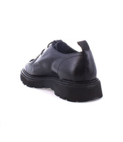 The Bed|Stü Casotto black leather dress shoe, featuring Italian craftsmanship and a thick rubber sole, is displayed from a rear side angle on a white background.