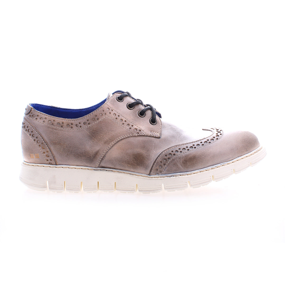 The Bed|Stü Cayuga II is a brown leather wingtip lace-up shoe featuring classic brogue detailing, a white sole, and blue inner lining, displayed in profile against a white background.