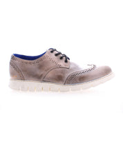 The Bed|Stü Cayuga II is a brown leather wingtip lace-up shoe featuring classic brogue detailing, a white sole, and blue inner lining, displayed in profile against a white background.