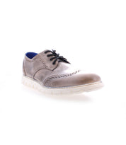 The Bed|Stü Cayuga II is a single brown leather derby shoe with brogue detailing, including a white sole, black laces, decorative perforations inspired by classic wingtip designs, and a blue inner lining, showcased against a white background.