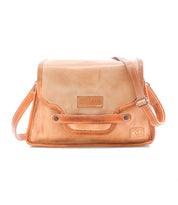 Bed|Stü’s Ceremonious is a tan leather preppy flap-top bag with an adjustable strap, front flap secured by a magnetic closure, stitched detailing, organized interior, and an embossed Bed|Stü logo on the front.