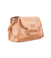 The Ceremonious by Bed|Stü is a light brown leather preppy flap-top bag, featuring a front flap with visible stitching and a small logo patch on the front. Its organized interior and secure magnetic closure offer added convenience.