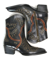 A pair of Chamise black leather ankle boots by Bed|Stü, featuring brown and gold decorative stitching, stud accents, and side zippers, are arranged overlapping on a white background—these stylish western boots offer a modern take on the classic mid-height boot silhouette.