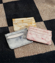 Three Chuck small leather cardholders by Bed|Stü—perfect as slim wallets or compact card holders in yellow, blue, and pink—are placed on a woven checkered surface, making them ideal for your everyday carry.