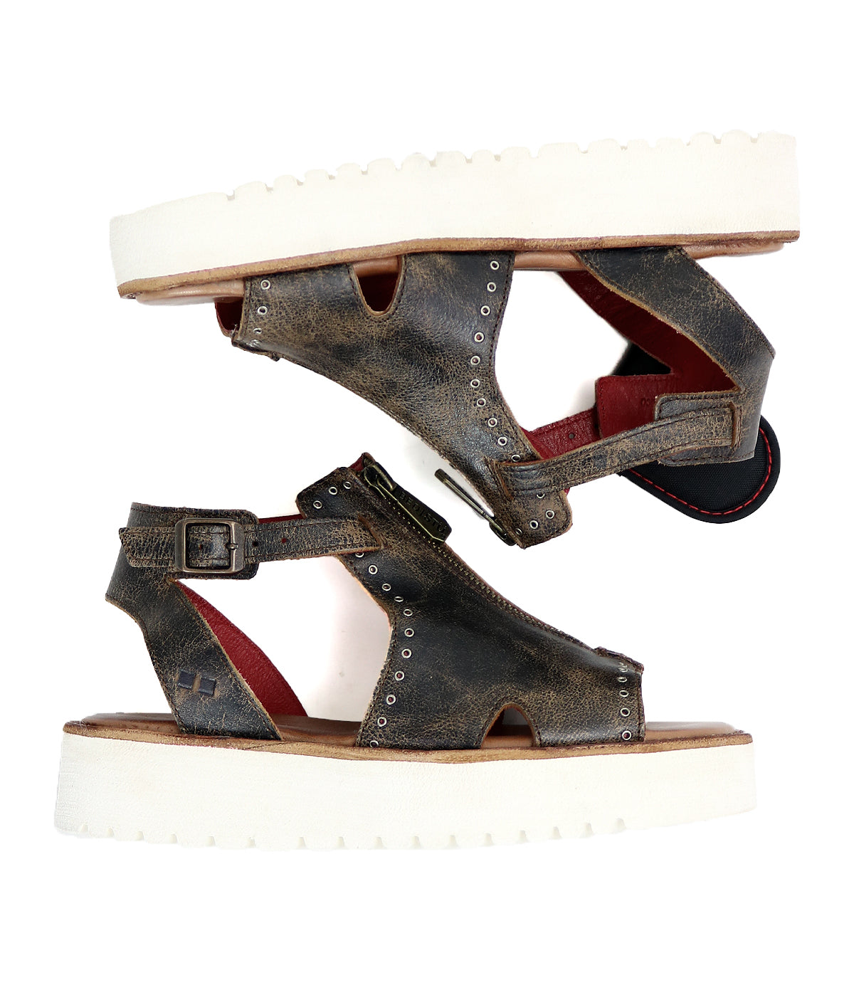 The Bed|Stü Clancy sandals are a pair of brown cutout leather shoes with white thick platform soles, accented by metal rivets, red inner lining, and adjustable buckles. Featuring a cushioned insole for added comfort, they are shown side by side on a white background.