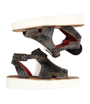The Bed|Stü Clancy sandals are a pair of brown cutout leather shoes with white thick platform soles, accented by metal rivets, red inner lining, and adjustable buckles. Featuring a cushioned insole for added comfort, they are shown side by side on a white background.