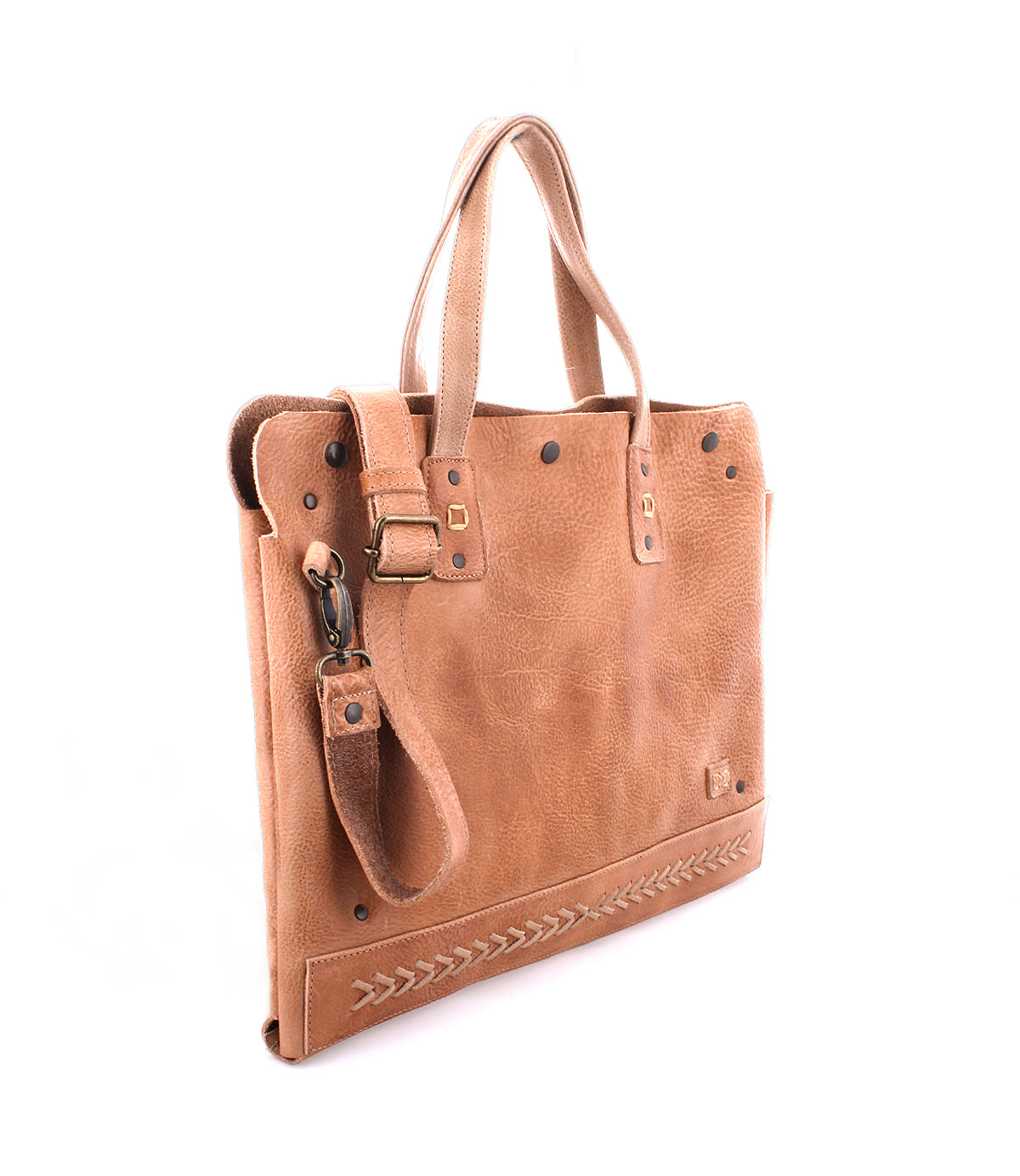 The Bed|Stü Commuter is a light brown leather bag featuring short handles, a detachable shoulder strap, metal stud accents, and decorative stitching along the bottom edge—ideal for stylishly carrying your essentials as a laptop bag or mobile office bag.