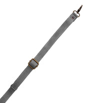 Bed|Stü Crossbody Strap: This gray adjustable fabric strap features a metal buckle and a small circular metal ring at one end. Shown on a white background, it's perfect for adding to your favorite Bed|Stü bags or swapping onto any crossbody for versatile style.