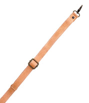 A tan leather Crossbody Strap by Bed|Stü, featuring an adjustable design with a metal buckle and a metal clasp at one end, is shown against a white background.