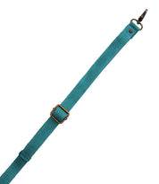 The Bed|Stü Crossbody Strap features a teal fabric strap with an adjustable brass buckle and a metal clasp on one end, making it perfect as a crossbody accessory or a replacement strap for your Bed|Stü bags. Shown on a white background.