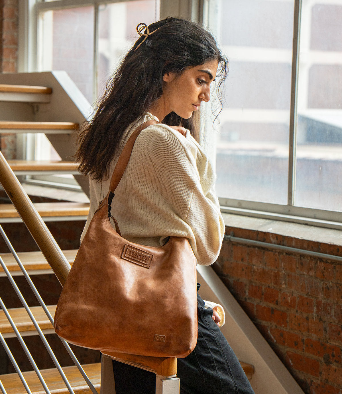 A person wearing a tan leather Dallas LTC shoulder bag over their shoulder.