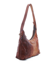 The Denton by Bed|Stü is a brown leather shoulder bag featuring a single strap, visible stitching, and a zip-top closure on the main compartment, expertly crafted from rich vegetable-tanned leather and photographed against a white background.