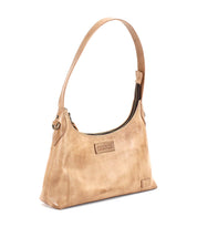 Introducing the Denton by Bed|Stü—a beige leather shoulder bag crafted from premium vegetable-tanned leather. This small bag features a single strap, a zip-top closure, and embossed brand patches on the front, effortlessly blending classic elegance with everyday functionality.