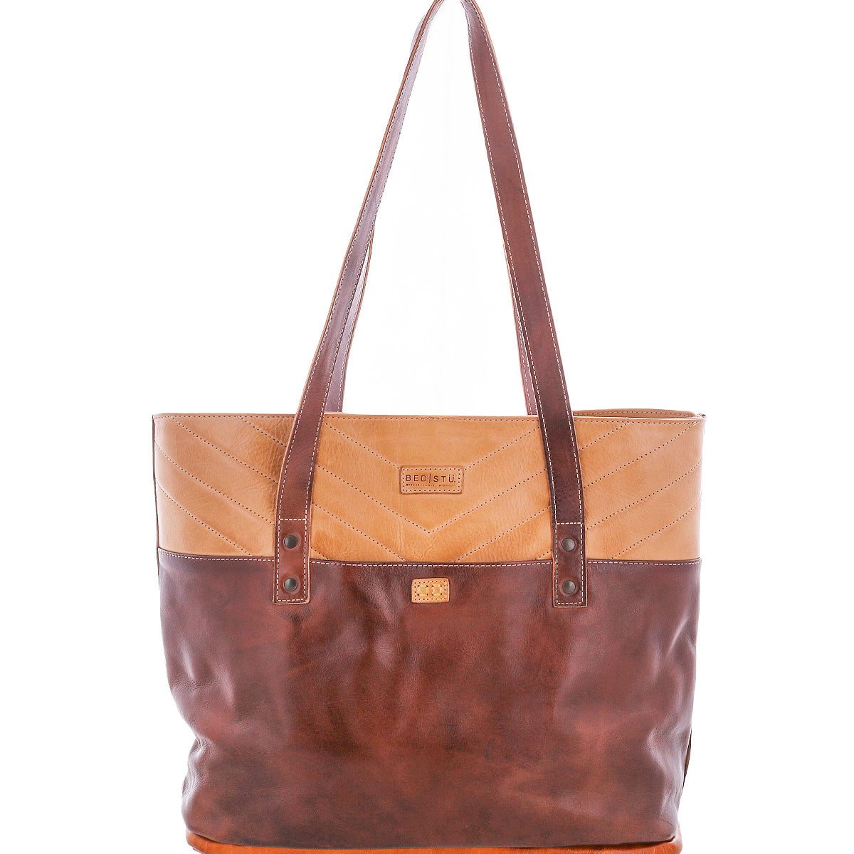 The Bed|Stü Dome tote is a two-tone brown leather bag with long handles, chevron stitching on the top section, and a small logo patch on the front. Designed with a spacious interior to hold all your work essentials, it is photographed against a white background.
