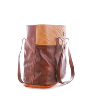 Introducing the Dome by Bed|Stü—a brown and tan leather shoulder bag with a long strap, featuring quilted detailing on the top section and a soft, unstructured shape. This stylish tote offers a spacious interior, making it perfect for carrying all your work essentials.