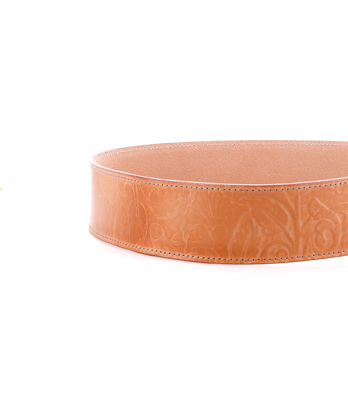 A close-up of the Dreampath EM by Bed|Stü, a round, light brown leather container featuring intricate floral embossing and expertly crafted from the same genuine leather found in modern style belts celebrated for their rugged durability. The piece is showcased against a white background.