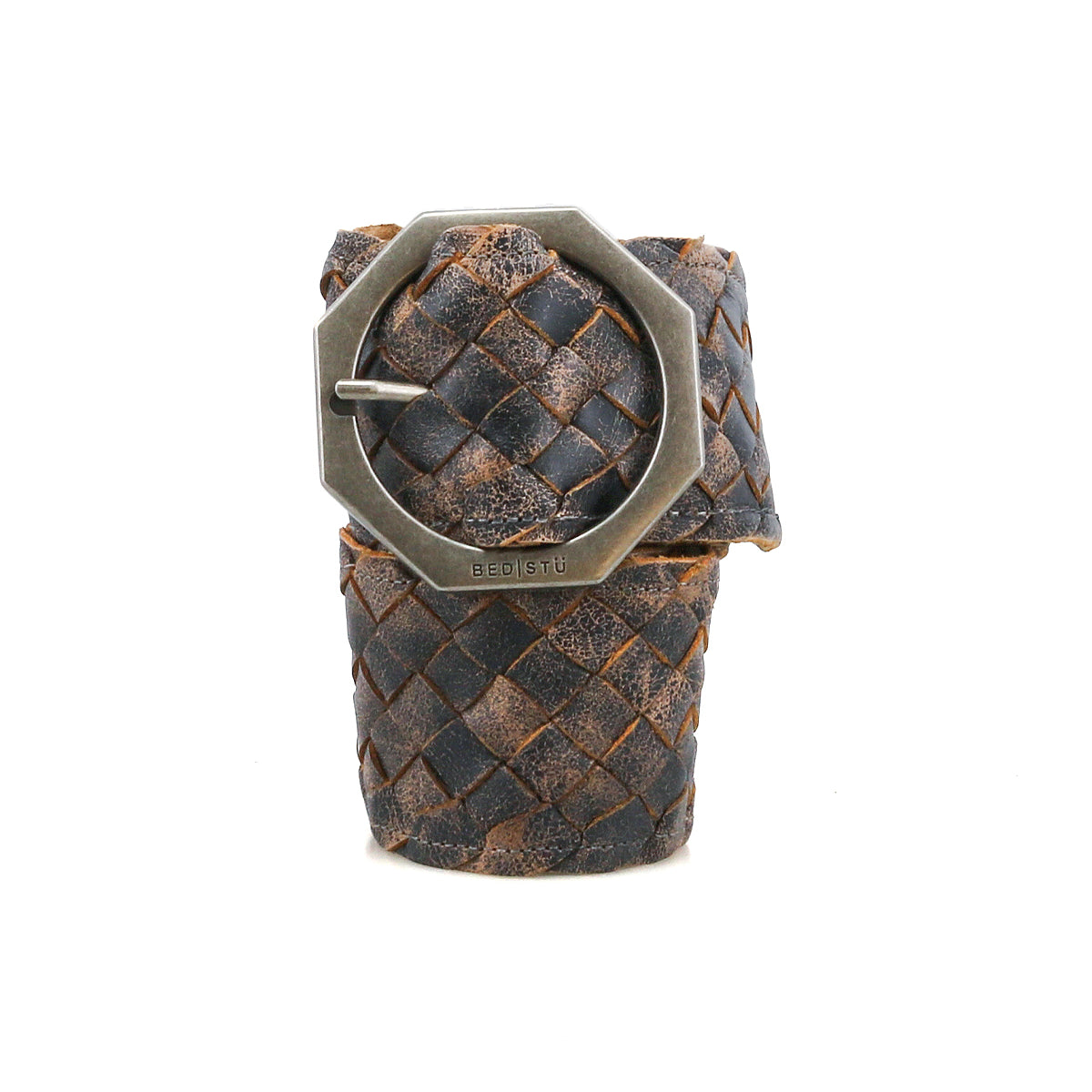 The Dreamweaver belt by Bed|Stü features woven dark brown leather and an octagonal metal buckle, highlighting artisan craftsmanship as it stands upright against a white background.