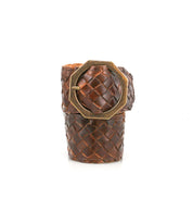 The Dreamweaver bracelet by Bed|Stü showcases artisan craftsmanship and bohemian style with its wide brown woven leather band, accented by a large octagonal brass buckle, and is displayed upright against a white background.