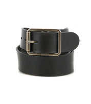 The Drifter by Bed|Stü is a black leather belt featuring a rectangular metal buckle, coiled in a circular shape against a plain white background. Its textured leather strap and minimal design make this Bed|Stü accessory truly timeless.