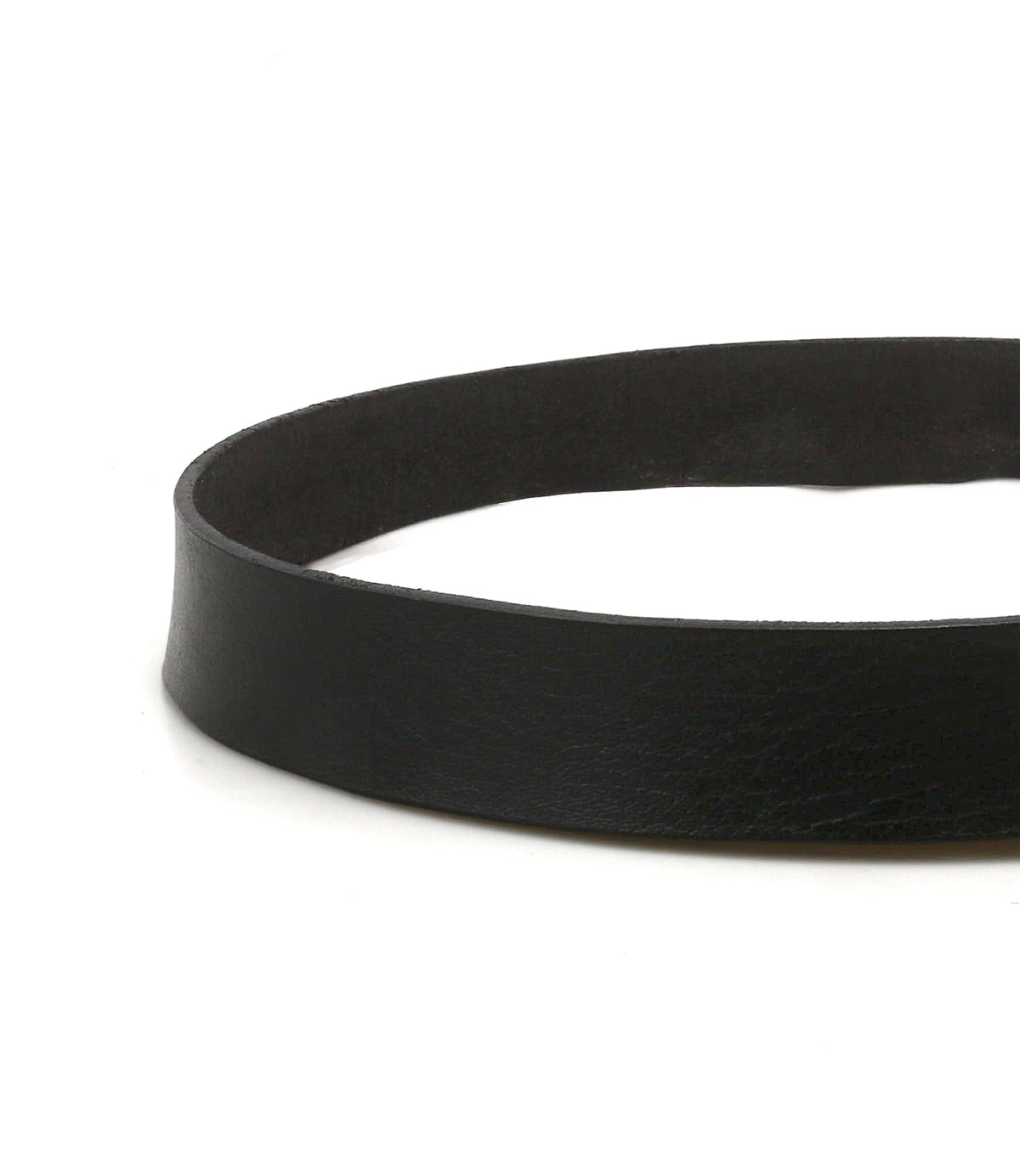 A close-up view of the Bed|Stü Drifter strap in black textured leather with a metal buckle, lying flat on a white surface and highlighting its minimal style and the intricate detail of its material.