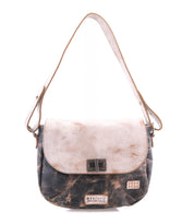 The Elect shoulder bag by Bed|Stü is a two-tone leather accessory with a flap closure, adorned with a rectangular metal clasp and a short strap, seamlessly combining vintage charm and everyday practicality.