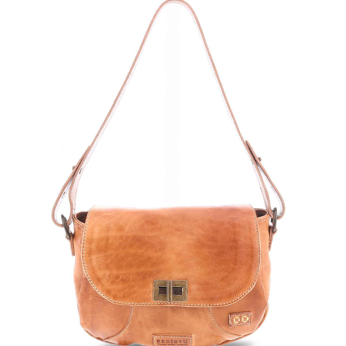 The Bed|Stü Elect is a light brown leather shoulder bag featuring a front flap, metal clasp, and adjustable strap. Shown against a white background, this bag is perfect for everyday use and designed with subtle vintage charm.