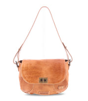 The Bed|Stü Elect is a light brown leather shoulder bag featuring a front flap, metal clasp, and adjustable strap. Shown against a white background, this bag is perfect for everyday use and designed with subtle vintage charm.