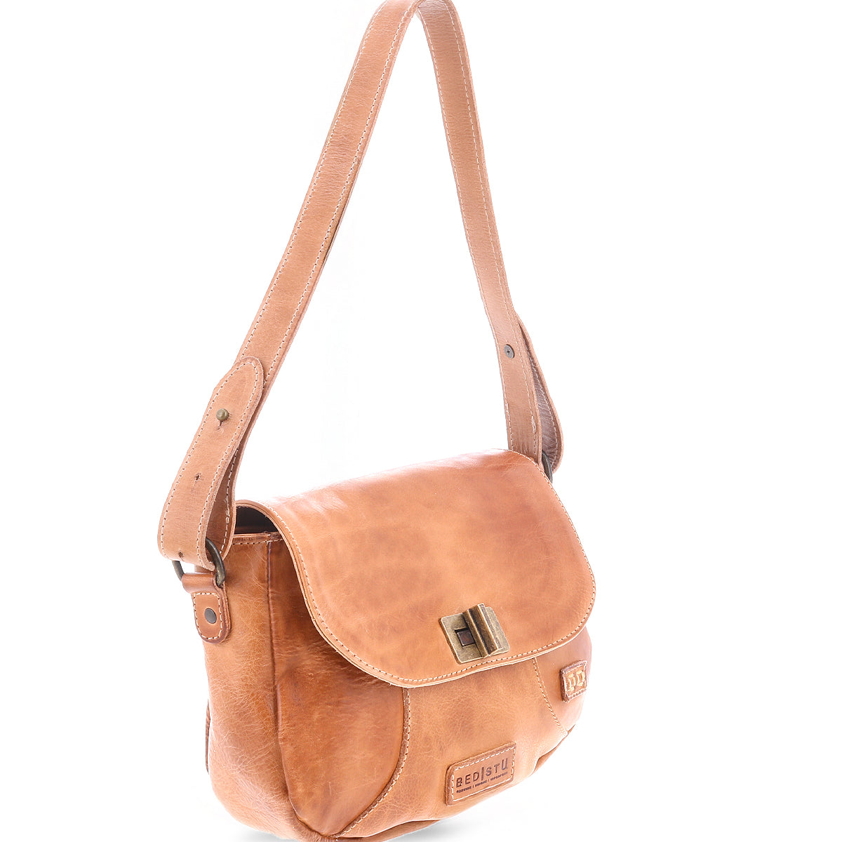 The Elect by Bed|Stü is a light brown leather shoulder bag featuring a front flap, metal clasp, and adjustable strap. Displayed on a white background, this piece blends vintage charm with everyday practicality.