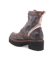 The Elisha Hi by Bed|Stü is a distressed brown lace-up boot featuring metallic accents and a classic lace-up profile, set on a thick, ridged black sole and displayed from a rear side angle on a white background.