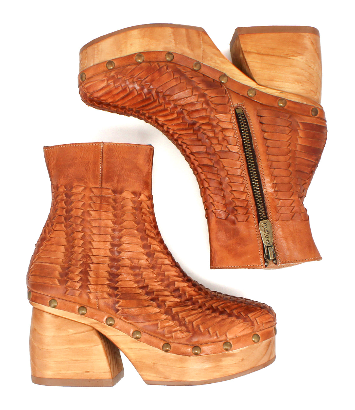 Two Ellasphin brown leather platform ankle boots by Bed|Stü, featuring a woven texture, brass studs, thick wooden heels, and visible side zippers, are displayed side by side on a white background—an eye-catching display of artisan fashion and sculptural footwear design.