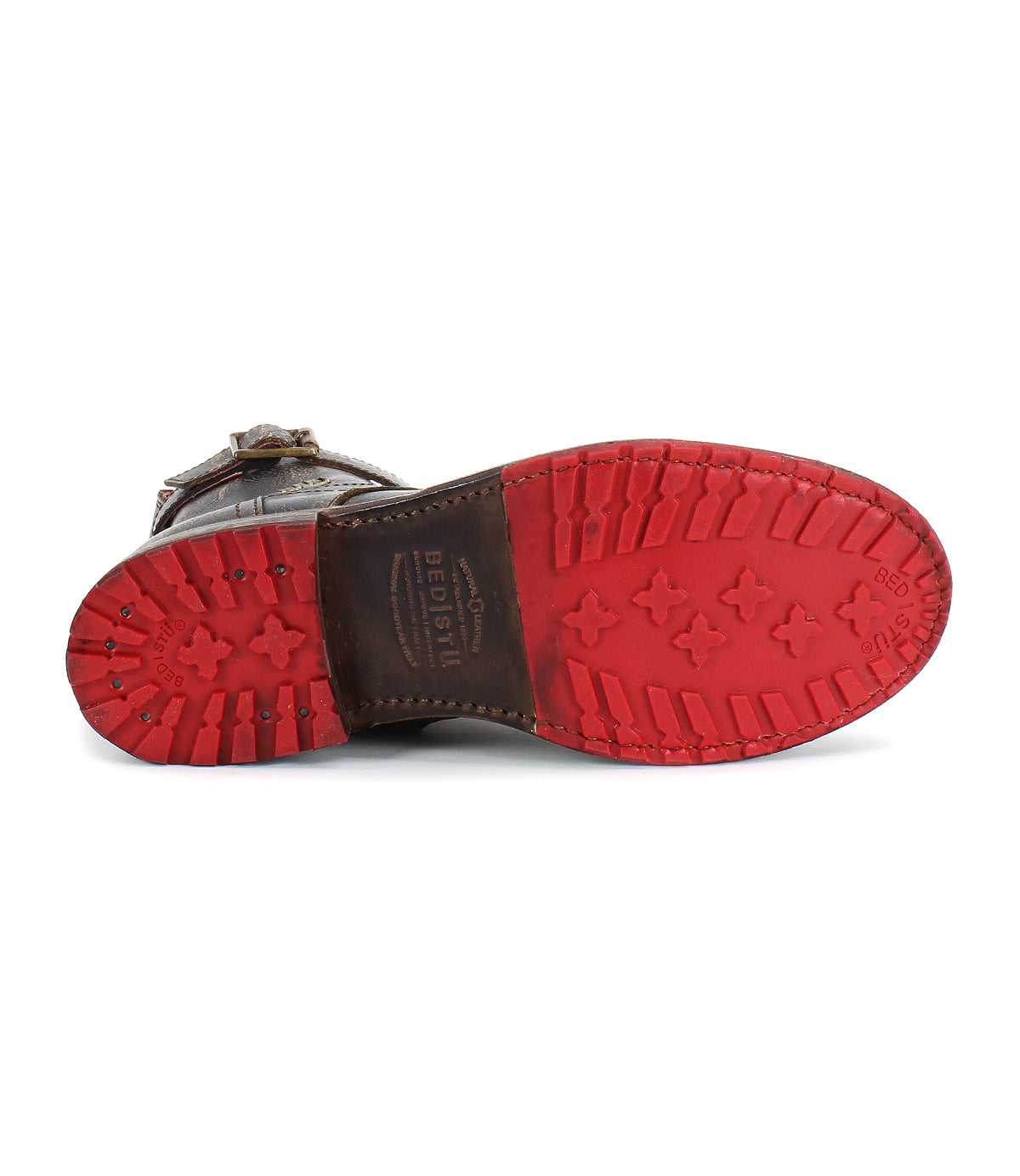 The Bed|Stü Endure boot is displayed sole up, highlighting its brown leather upper and rugged craftsmanship. The durable red rubber outsole features cross-shaped treads and brand markings, providing a reliable, treaded grip.