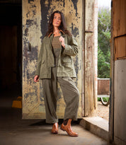 A woman stands in a doorway with one hand in her pocket, her neutral expression effortlessly highlighting the Ethic Chelsea boots by Bed|Stü, featuring a durable design and leather-lined finish.