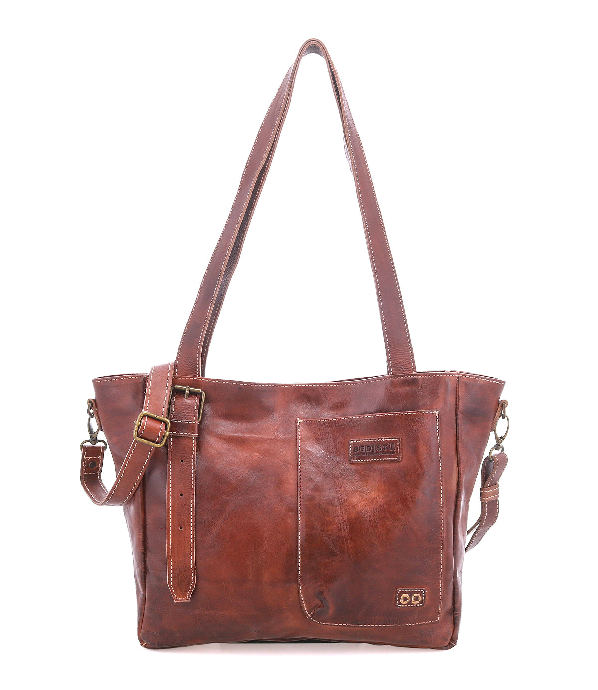 Meet the Explicit LTC by Bed|Stü—a brown leather shoulder bag featuring two sturdy handles, an adjustable strap, and a front pocket. Visible stitching and a small embossed Bed|Stü logo enhance its rustic charm. Designed for everyday dependability, this piece stands out beautifully against a plain white background.