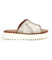 The Bed|Stü Fairlee II is a metallic silver slip-on slide sandal featuring an open toe, a wide upper strap, a brown cushioned footbed insole, and a thick white platform sole with ridged tread.