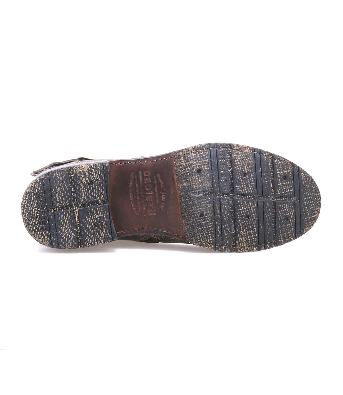 Bottom view of a worn, textured rubber and leather shoe sole—crafted with Goodyear welt construction—showing visible tread patterns and the word "Bed|Stü" embossed in the center. This rugged staple captures the essence of the classic Fellow moto boot.