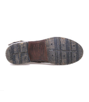 Bottom view of a worn, textured rubber and leather shoe sole—crafted with Goodyear welt construction—showing visible tread patterns and the word "Bed|Stü" embossed in the center. This rugged staple captures the essence of the classic Fellow moto boot.
