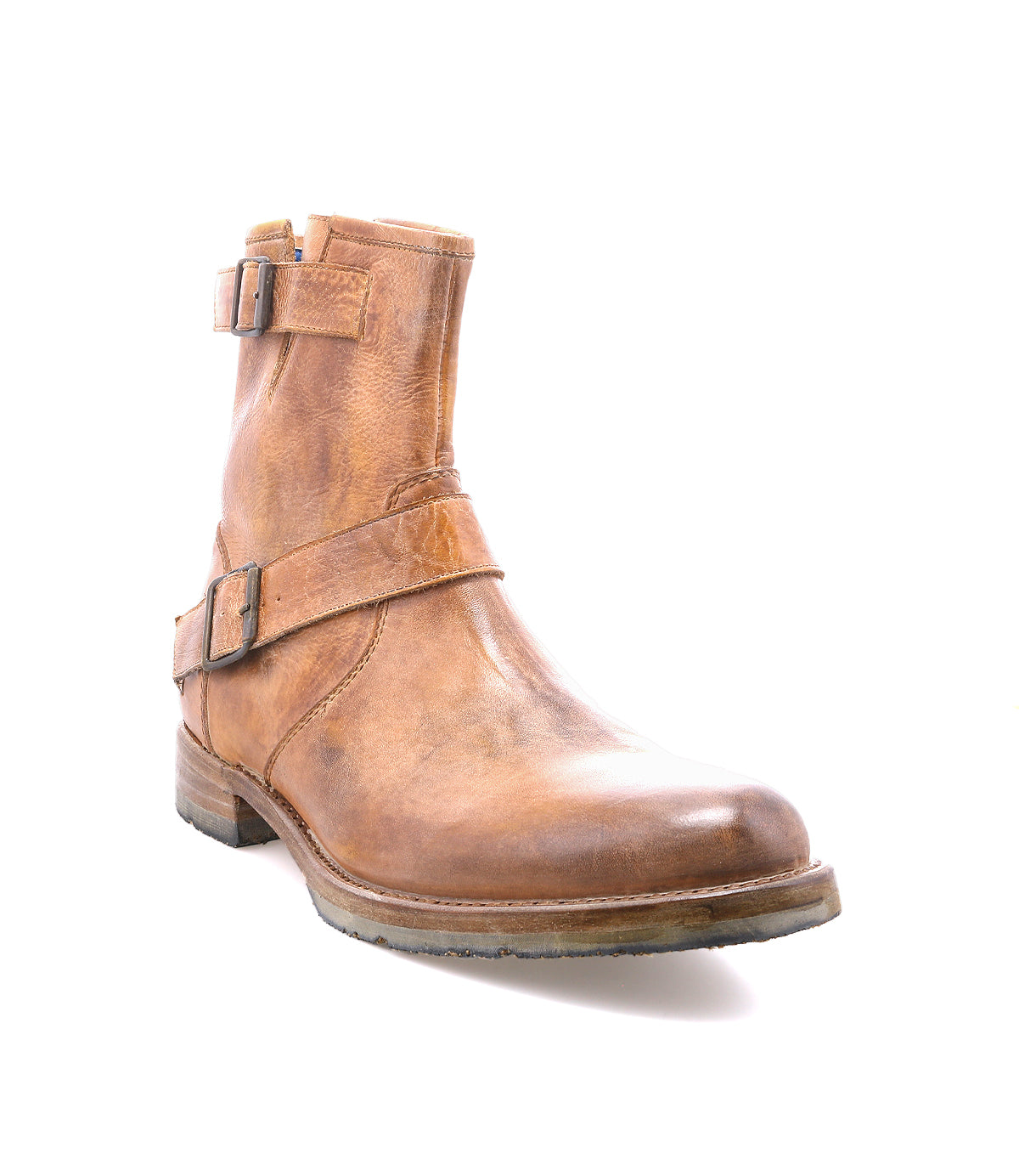 The Bed|Stü Fellow is a brown leather moto ankle boot featuring two side buckles, a rounded toe, and a low heel. Crafted with durable Goodyear welt construction, it is photographed on a white background.