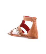 The Bed|Stü Fibril is a brown flat sandal crafted from hand-woven leather, featuring an adjustable ankle strap, open sides, and a closed heel for a bohemian look; pictured at an angle against a white background.
