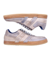 Two stylish beige "Firepower" everyday sneakers by Bed|Stü, featuring tan rubber soles, subtle leather stripe details, and a textured sole—one shoe upright and the other on its side—set against a crisp white background.