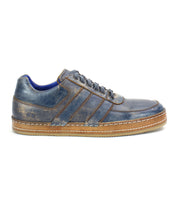 The Bed|Stü Firepower is a blue leather everyday sneaker featuring a brown textured sole, decorative stitching, leather stripe accents, and laces, displayed in a left side profile view against a white background.