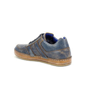 The Bed|Stü Firepower is an everyday blue leather sneaker with brown stitching, featuring subtle leather stripe details and a tan textured rubber sole, shown from the back left side against a white background.