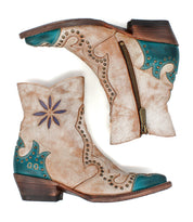The Bed|Stü Frio booties in tan and turquoise feature decorative stitching, floral cutout accents, antiqued brass studs, and convenient side zippers, shown from both sides against a white background.