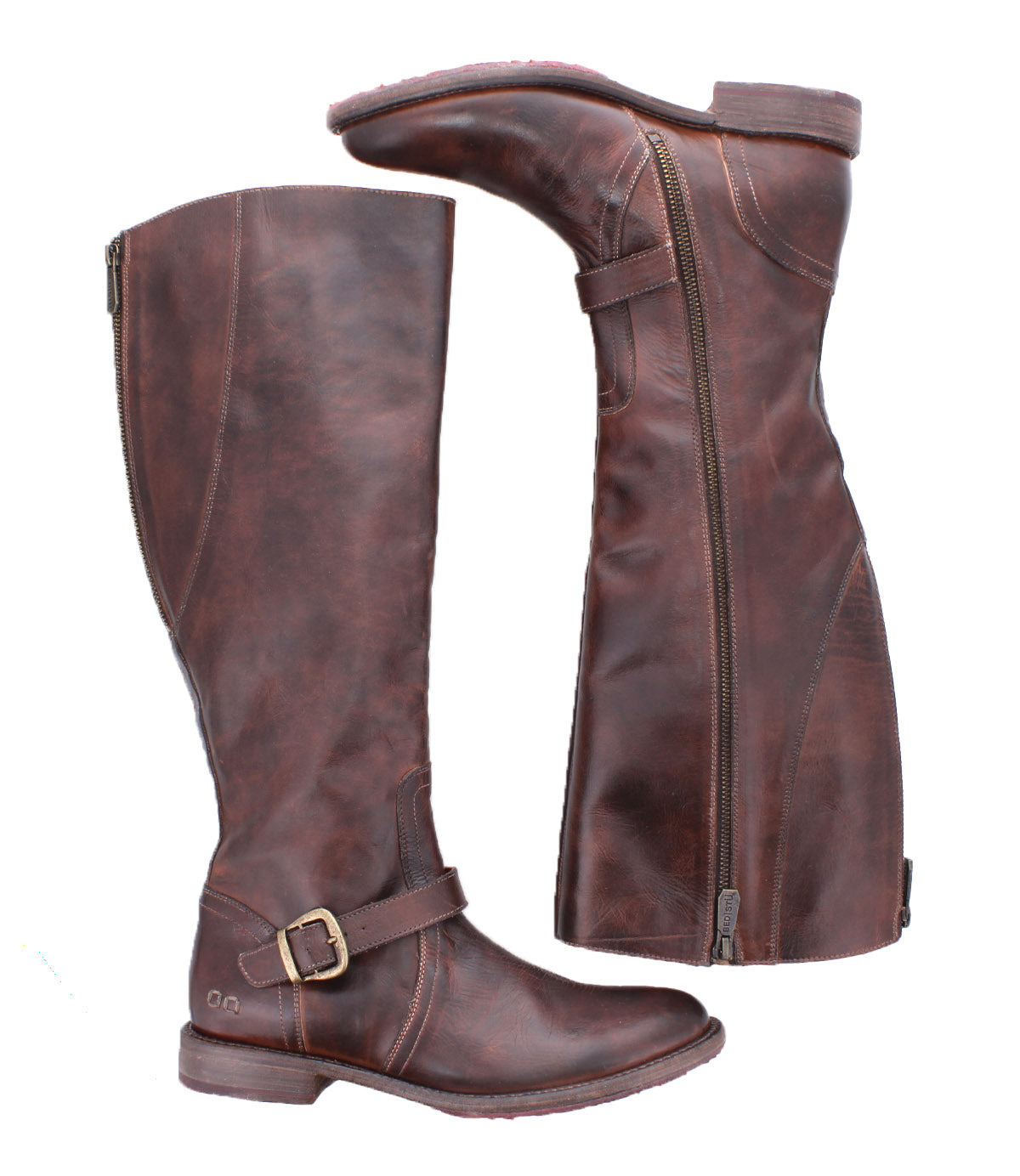 The Bed|Stü Glaye is a pair of tall leather boots with side zippers and vintage buckles, displayed from both a side and sole view against a white background. These equestrian-inspired boots showcase classic detailing and timeless style.