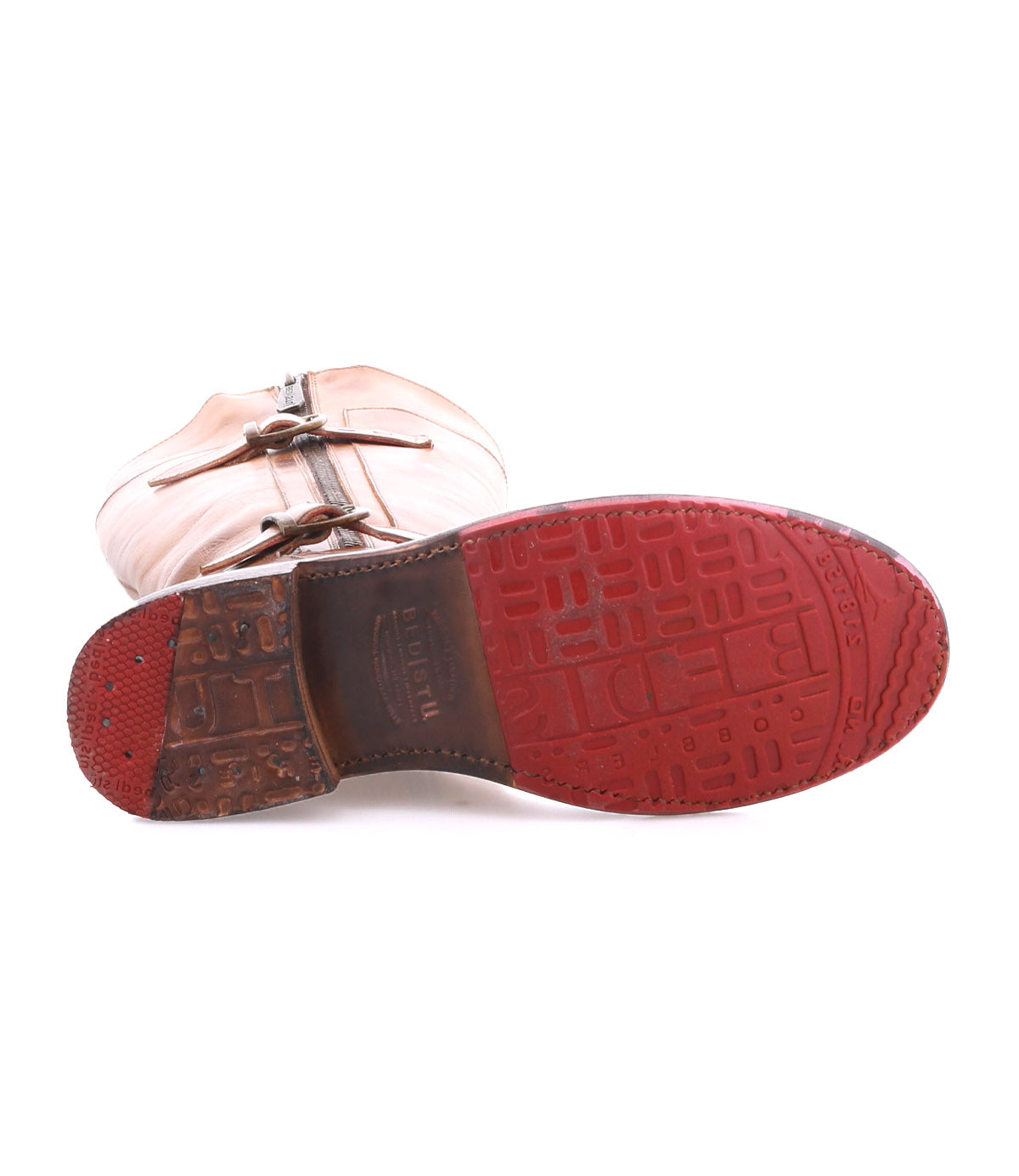 The Bed|Stü Gogo Lug is a tan mid-calf leather boot, pictured from the bottom to showcase its distinctive red rubber lug outsole with geometric tread patterns and visible wear on the heel.