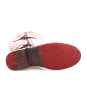 The Bed|Stü Gogo Lug is a tan mid-calf leather boot, pictured from the bottom to showcase its distinctive red rubber lug outsole with geometric tread patterns and visible wear on the heel.