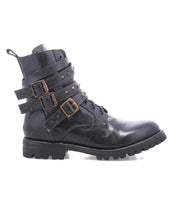The Bed|Stü Grab is a black leather combat boot featuring three studded buckle straps with metal buckles, a lace-up front, and a chunky Vibram sole for superior traction. Shown in side profile on a white background.