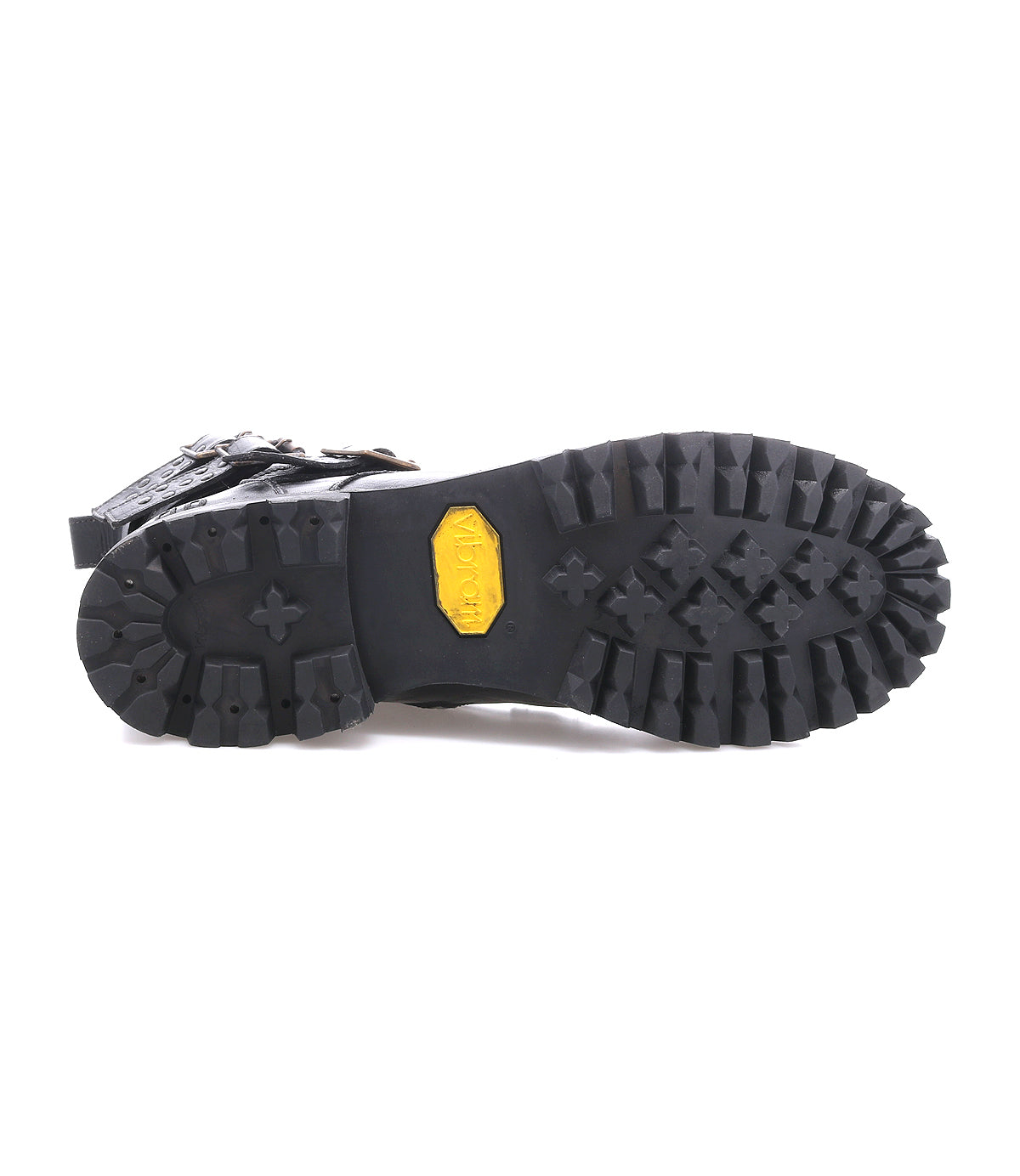 Close-up of the Bed|Stü Grab boot’s rugged black rubber sole with deep treads and a yellow Vibram logo at the center, showcasing studded buckle straps along the upper for added edge.